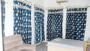 Une chambre avec un lit, une chaise et des rideaux à motifs losangés.