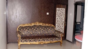 Une pièce avec un canapé à motifs, une porte ornée d’un panneau décoratif et un sol carrelé.