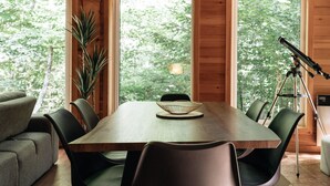 A dining area with a wooden table, chairs, and a telescope.