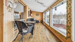 A cozy room with wooden walls, a dining table with chairs, and large windows with ivy. - Waterfront - Spa | Havre de l'Auror | Harry Potter (Outaouais)