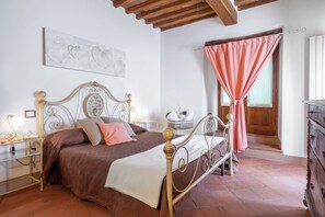 Classic bedroom with a four-poster bed, dresser, and nightstand, featuring a decorative headboard and a lamp.