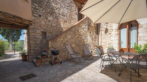 Une terrasse extérieure avec des murs en pierre, un barbecue et du mobilier d’extérieur.