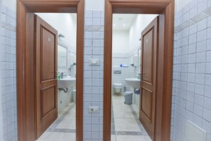Ein Badezimmer mit zwei Waschbecken, einer Toilette und einem Mülleimer.