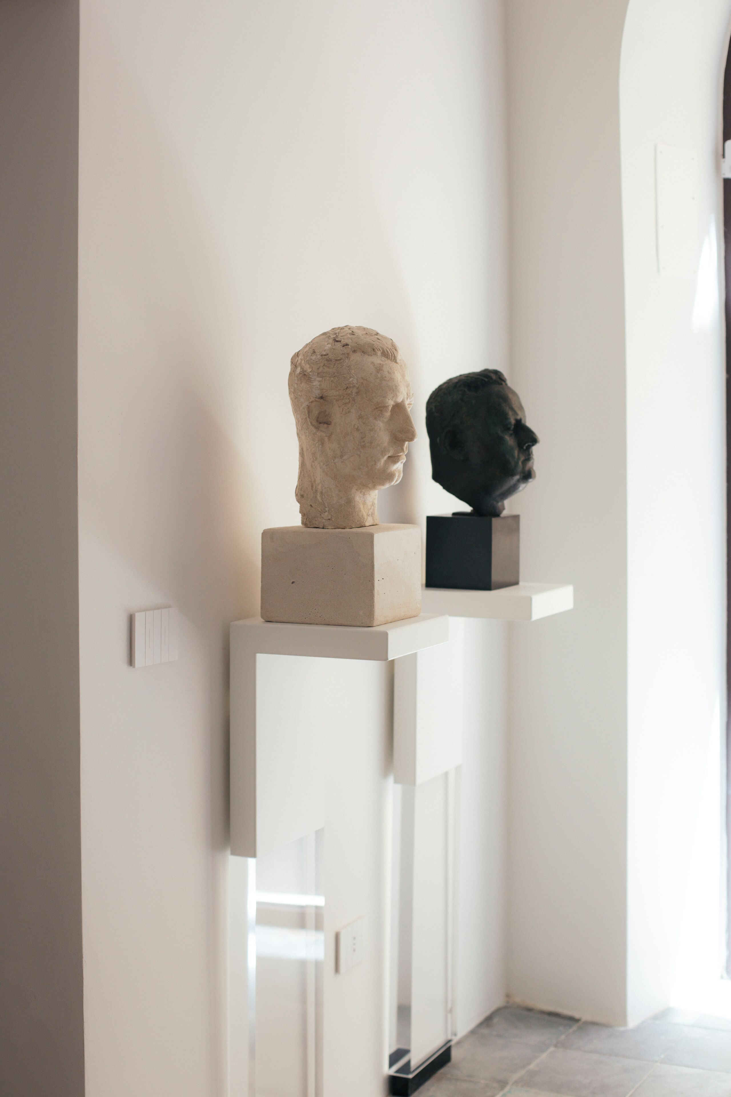 A hallway with two bust sculptures on white pedestals.