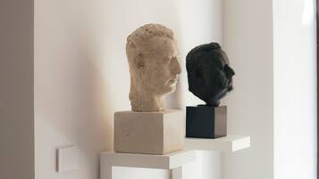 A hallway with two bust sculptures on white pedestals.
