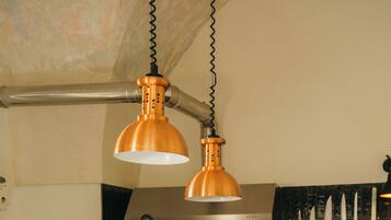 Una cocina con encimera de madera, lámparas colgantes de cobre y electrodomésticos de acero inoxidable.