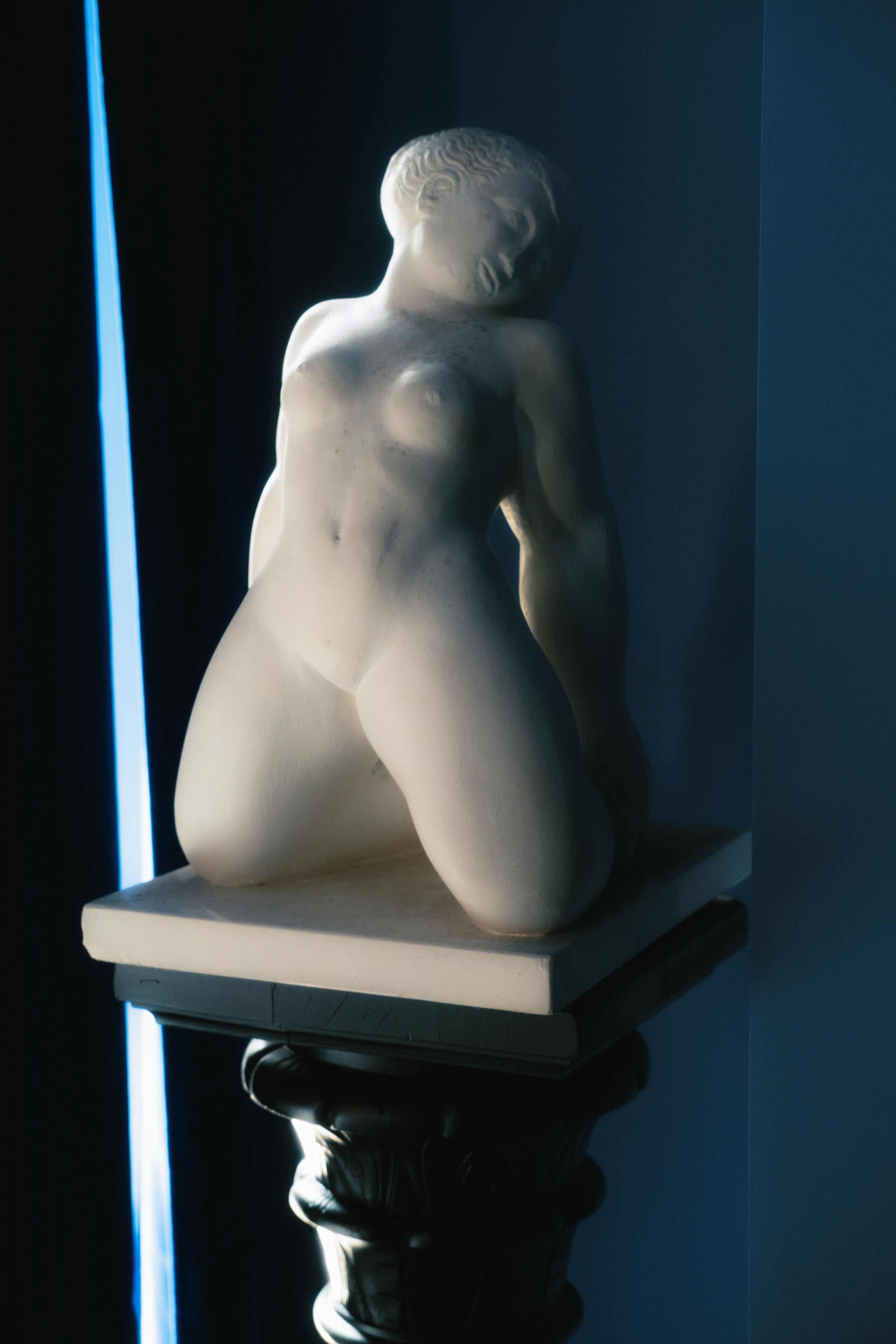 Una escultura de una figura reclinada sobre un pedestal.