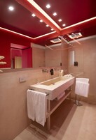Un baño moderno con tocador amplio, un espejo grande e iluminación empotrada en el techo.