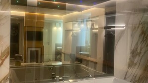 A modern bathroom with a glass-enclosed bathtub, a large mirror, and recessed lighting. - Elegant Suite in the heart of Naples  (Napoli)