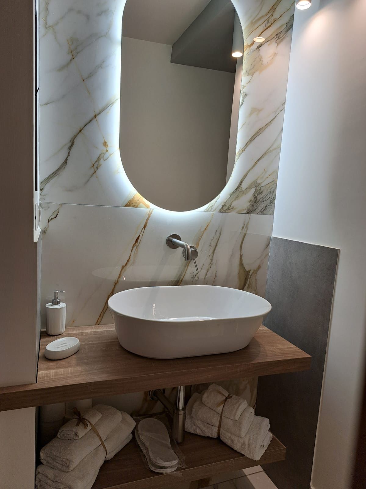 Une salle de bain avec un pare-baignoire en marbre, un lavabo sur pied, un miroir et un porte-serviettes avec des serviettes.