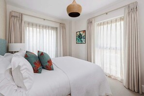 A bedroom with a large bed, beige curtains, a woven light fixture, and a framed artwork on the wall. - Hill View House - Cookswood, Somerset | Hot Tub | Sleeps 8 (Somerset)