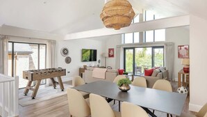 A spacious living area with a foosball table, a dining table, and a sofa set. - Hill View House - Cookswood, Somerset | Hot Tub | Sleeps 8 (Somerset)
