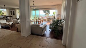 A spacious living area with a balcony overlooking a scenic view, furnished with sofas and chairs, and a dining area in the background. - Beautiful 6 Bedrooms Villa on the Cap d'Antibes with panoramic sea views (Antibes)
