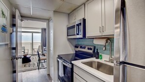 A compact kitchen with a refrigerator, microwave, stove, and sink.