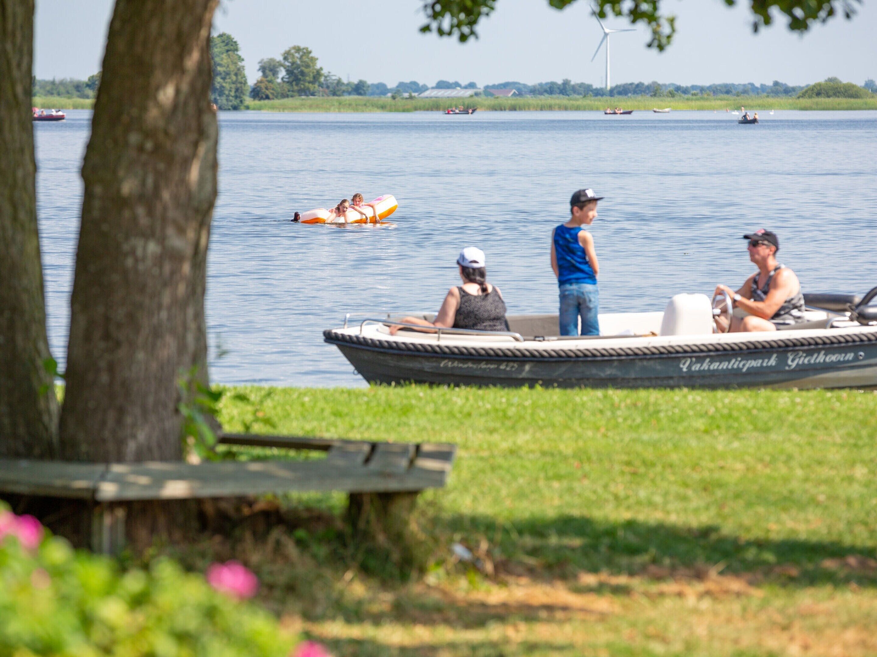 A boat with the name "Pakhantpark Giethoek" on its side, docked near a grassy area with a tree in the foreground.