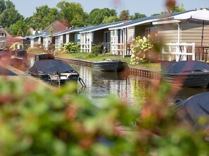 Un canal bordé de bateaux et une rangée de maisons reliées par une galerie couverte.