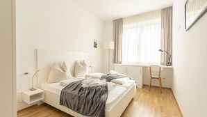 A minimalist bedroom with a bed, bedside table, lamp, and a desk with a chair. - Pleasant Chalet on the ski Slopes (Sankt Lambrecht)
