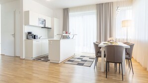 A modern kitchen with white cabinets, a coffee machine, and a dining area with a table and chairs. - Pleasant Chalet on the ski Slopes (Sankt Lambrecht)