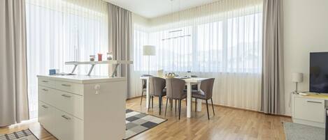 Una habitación moderna y bien iluminada con kitchenette, comedor y televisor.