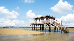 A wooden pier leading to a building with a balcony, situated on a sandy beach with clear skies. - Gorgeous home in Lege-Cap-Ferret with WiFi (Lege-Cap-Ferret)