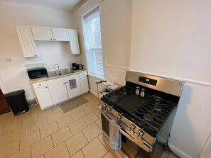 A kitchen with white cabinets, a stove, and a window.
