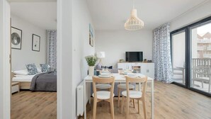 Un apartament modern amb zona de menjador, televisió i una finestra gran.