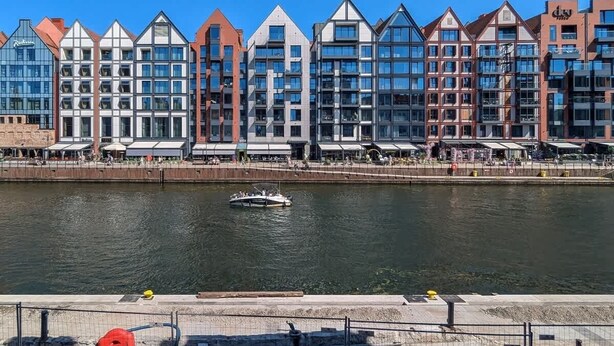 A waterfront hotel with modern architecture, a dock, and a boat.