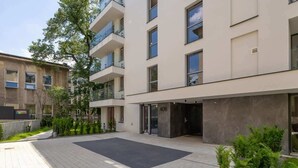 Un moderno edificio de apartamentos con patio interior, balcones y acceso en planta baja.
