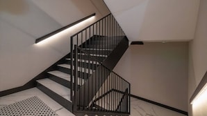 Una escalera moderna con barandillas negras y un diseño geométrico en el techo.