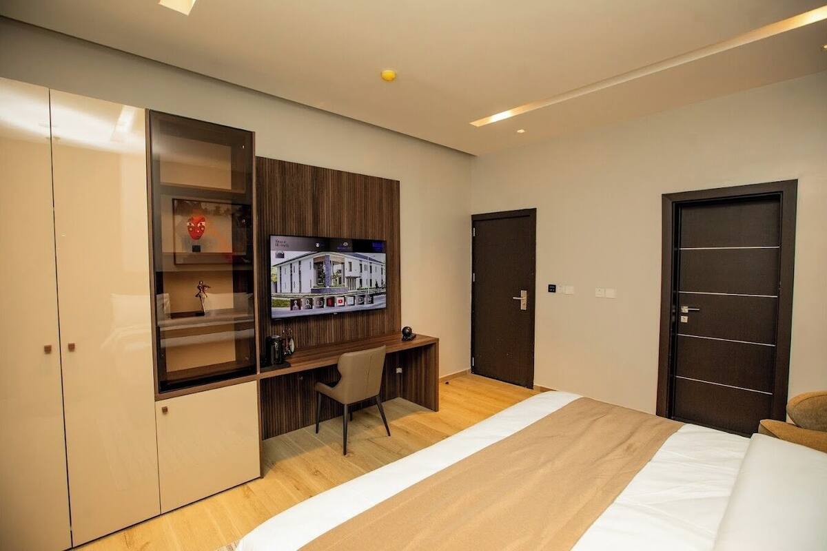 A modern bedroom with a bed, a desk, a chair, and a wardrobe.