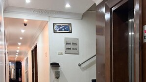 Un pasillo de hotel con ventilador de techo, un cuadro enmarcado, un ascensor y una escalera.