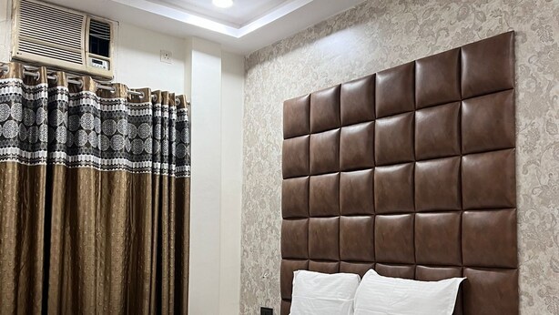 Un dormitorio ordenado con una cama grande, una mesita de noche, un ventilador de techo y cortinas estampadas.