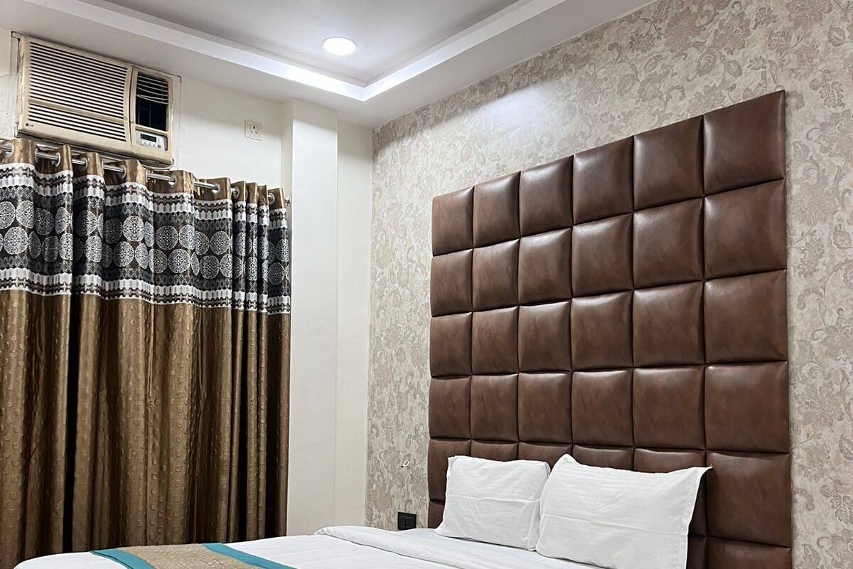 A neatly arranged bedroom with a large bed, a nightstand, a ceiling fan, and patterned curtains.