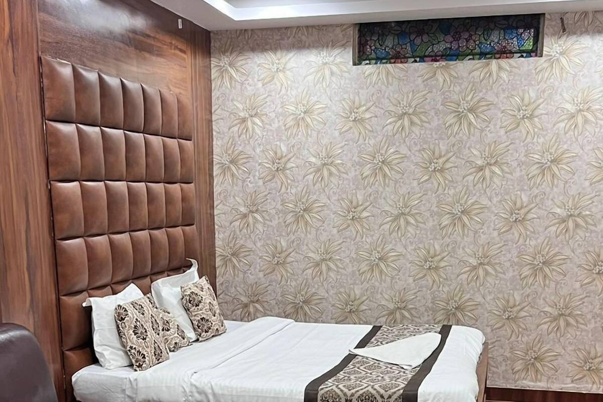 A hotel room with a bed, a glass coffee table, a leather chair, wooden flooring, and a ceiling fan.