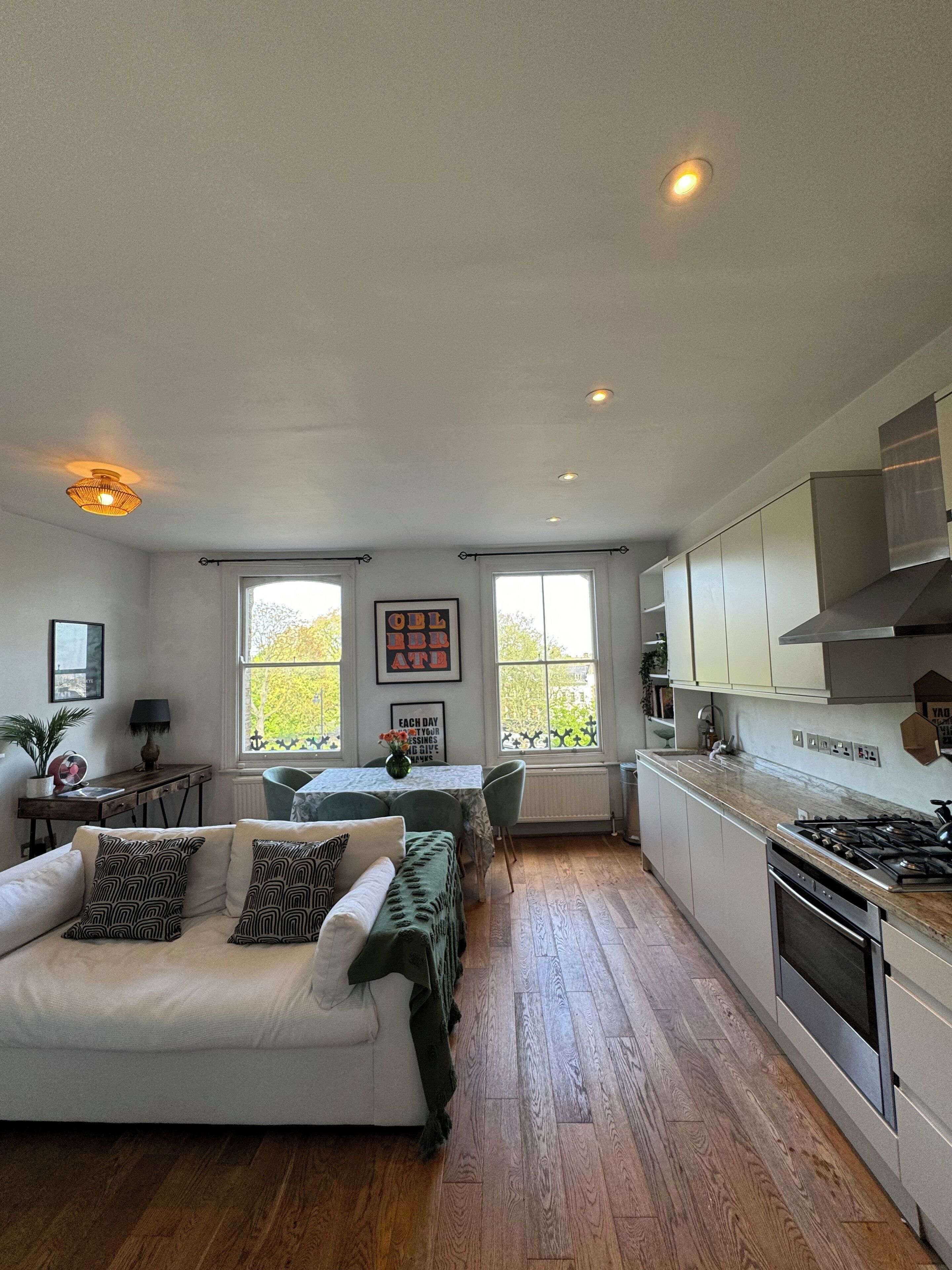 En rummelig opholdsstue med sofa, spisebord og et køkken med moderne hårde hvidevarer.