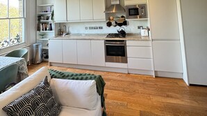 Moderni keittiö, jossa on valkoiset kaapit, sisäänrakennettu uuni ja mikroaaltouuni.