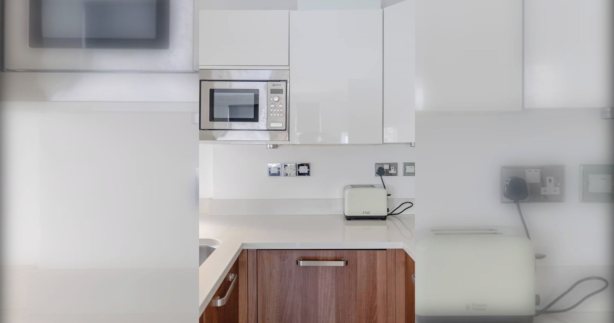 Una cocina moderna con microondas integrado, tostadora y armario de madera.