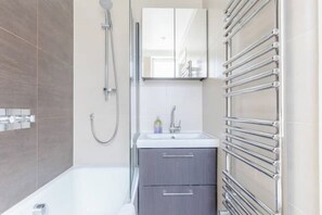 A modern bathroom with a bathtub, a shower, a sink, and a mirror.