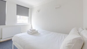 A hotel room with a bed, a window, and a radiator. - Central 2BD Flat, 10 Mins to Buckingham Palace! (London)