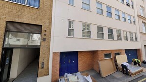 A multi-story building with a brick facade, a garage door, and a blue door marked with the number 10. - Central 2BD Flat, 10 Mins to Buckingham Palace! (London)