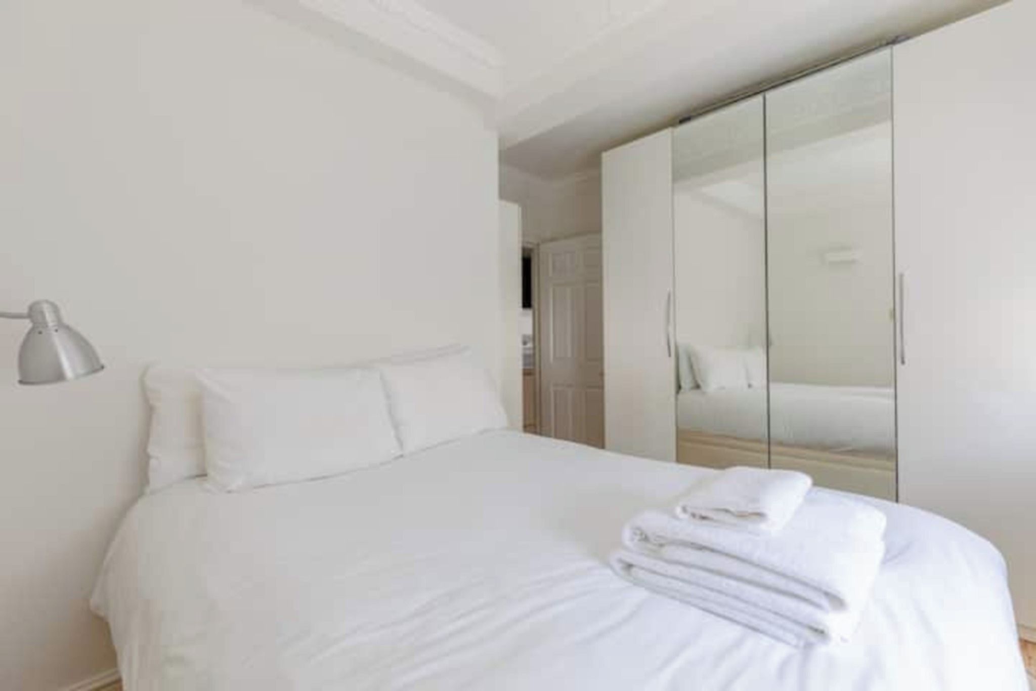 A bedroom with a bed, a bedside lamp, and a wardrobe.