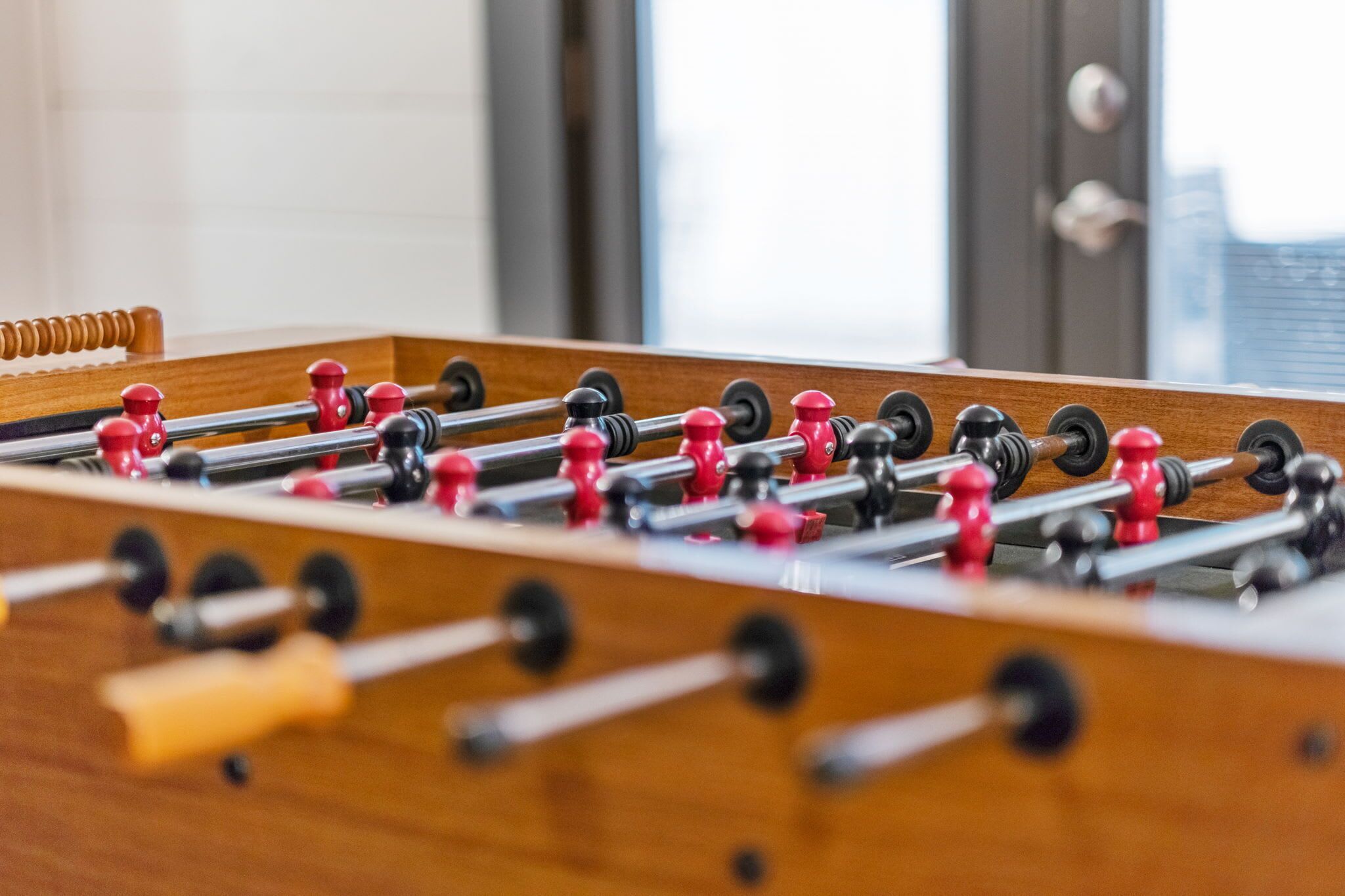 A close-up of a wooden foosball table with red and black figures.