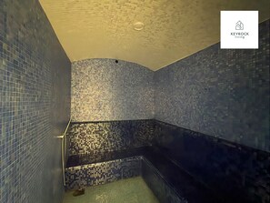 A tiled bathroom with a corner shower and a visible drain. - 1BDR apartment With Pool View (Dubai)