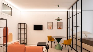 A modern room with a sofa, a small table, chairs, a TV, and a bed. - Loft 404 by Wonderful Italy (Bari)