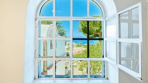 A window with multiple panes, offering a view of a coastal landscape with buildings and greenery. - Casa Alessandra in Anacapri (Anacapri)