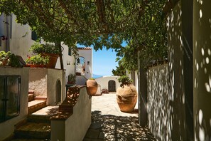 A narrow alleyway with steps leading to a white building with a tiled roof, surrounded by potted plants and large pots. - Casa Alessandra in Anacapri (Anacapri)