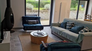 Una sala de estar moderna con un sofá, un sillón, una mesita redonda y una chimenea.