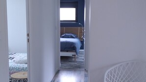 Un pasillo estrecho que conduce a un dormitorio con una cama, una silla y una mesita.