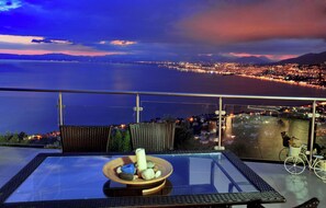 A balcony with a glass table, wicker chairs, and a bicycle. - Ilektra Studio Apt with Sea View (Kalamata)