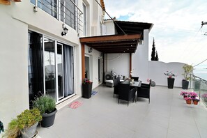 A balcony with a dining area, potted plants, and a view of the sea. - Ilektra Studio Apt with Sea View (Kalamata)